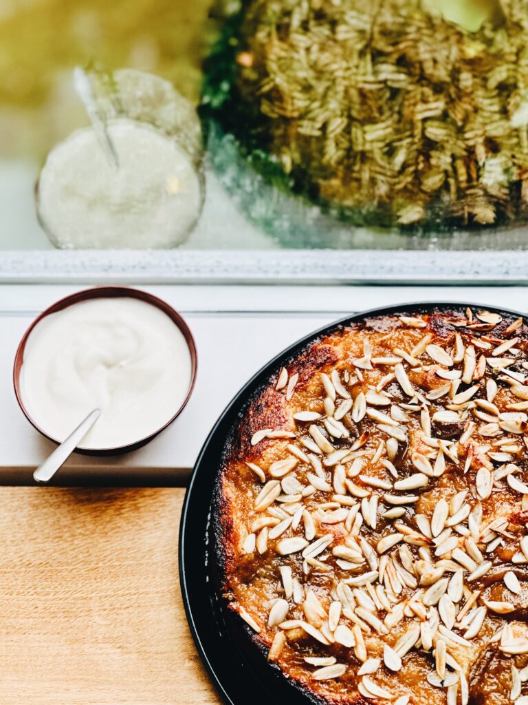 Blommetærte med mandelsplitter og skål med creme fraiche i vinduskarm